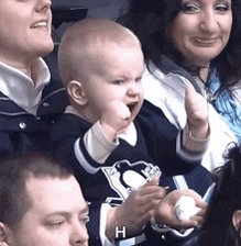 iced coffee with a white lid, baby wearing blue and white Penguin jerseys, and smiling woman in white jacket.