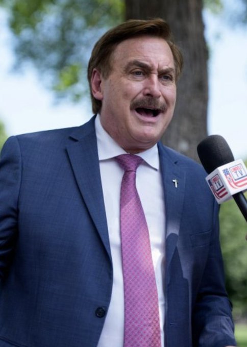MyPillow CEO Mike Lindell, dressed in a blue suit and pink tie, speaks into an "AM 1130" microphone after losing Minnesota's GOP gubernatorial primary to Lisa Demuth, according to a Polymarket projection giving Demuth a 99% chance of victory.