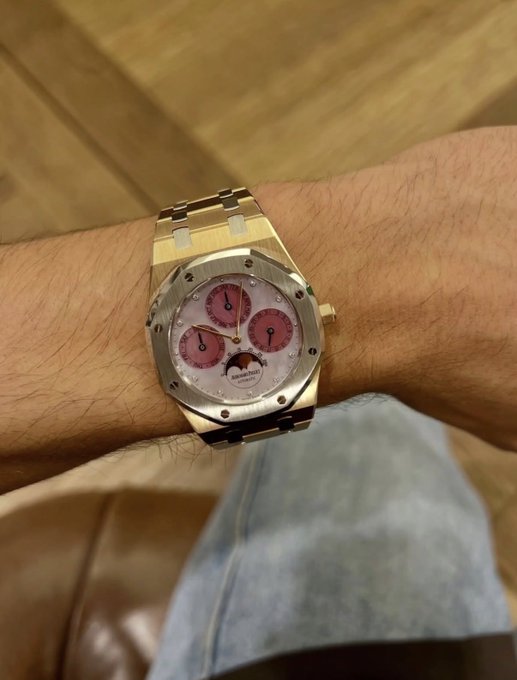 A gold Audemars Piguet Royal Oak watch with pink subdials is displayed on someone's wrist, serving as a visual incentive to entice new followers to engage with the giveaway post. The text "AUDEMARS PIGUET" is visible on the watch face, reinforcing the luxury appeal meant to attract participants willing to like and comment "Hi."