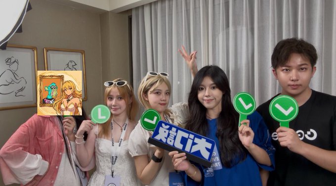 A group photo of five people holding green checkmark paddles, with one person holding a framed anime artwork and another holding a blue sign with Chinese characters '关注门才' (Follow Mengcai).