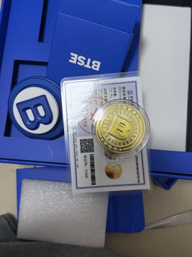 A gold Bitcoin commemorative coin in a clear display case rests on top of blue BTSE-branded packaging. The coin features the Bitcoin "₿" symbol and is presented alongside a printed certificate, matching the post's appreciation for BTSE merchandise.
