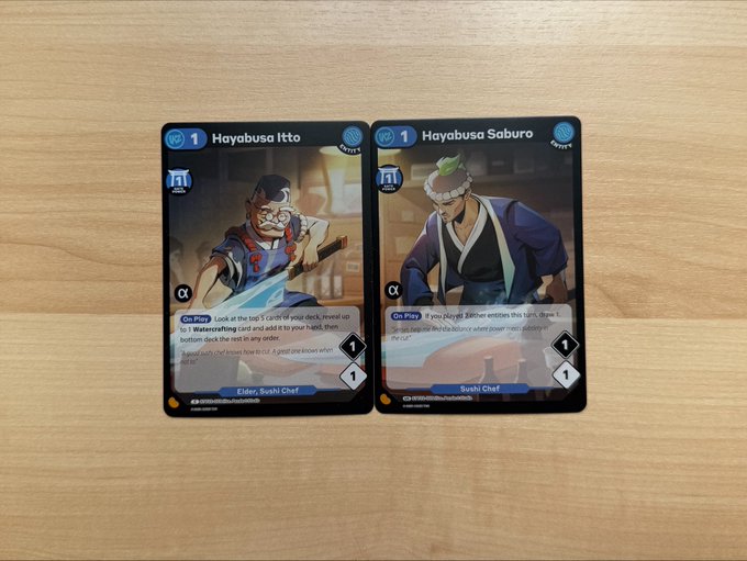 Two trading cards ('Hayabusa Itto' and 'Hayabusa Saburo') from a Sushi Chef set lying on a wooden surface.