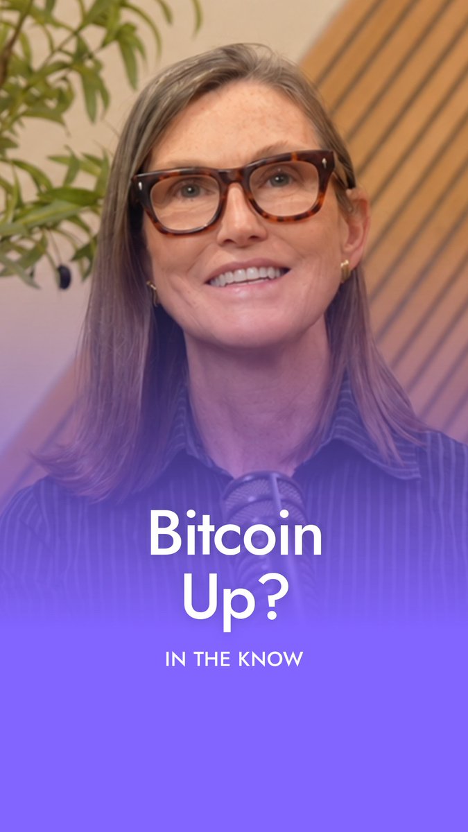 A woman identified as Cathie Wood is seen speaking into a microphone beneath a purple overlay with text reading "Bitcoin Up? IN THE KNOW," illustrating her bullish outlook on Bitcoin while noting that gold has been moving in the opposite direction.
