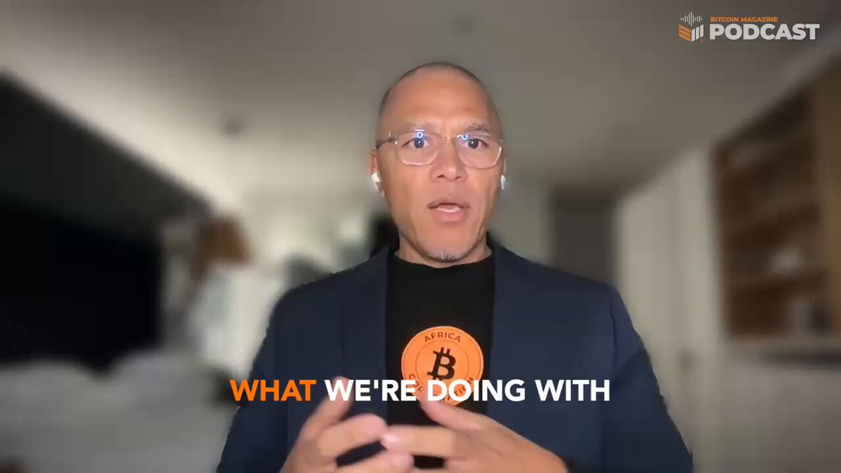 The image shows a man wearing glasses standing in front of a white wall with a blackboard or chalkboard background. The man appears to be giving a speech or presentation about Bitcoin, possibly related to Africa. The text "What we're doing with Bitcoin" is written on the image, indicating that the man is discussing the use and potential applications of Bitcoin within African markets.