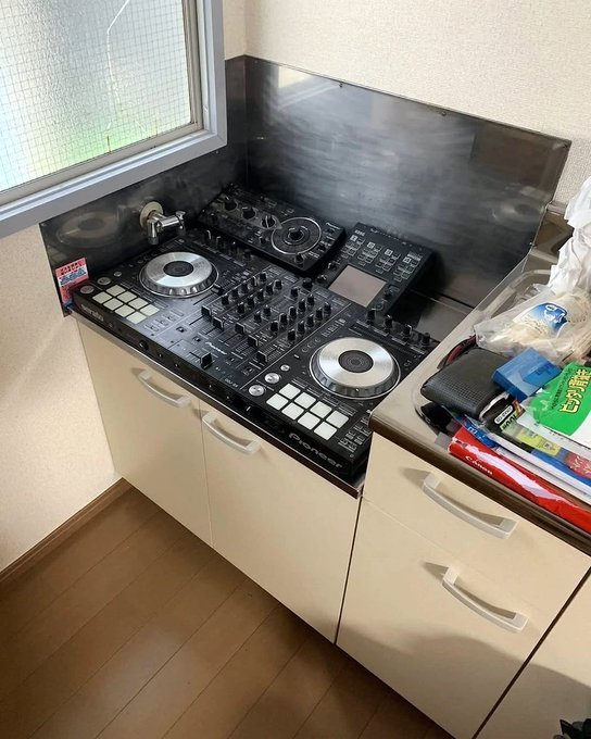 A custom kitchen installation using Pioneer DJ equipment (turntables and mixers) as the countertop surface, with a stainless steel backsplash and white cabinets below.