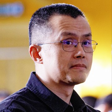 The image shows a man with short hair and glasses, wearing a dark collared shirt, looking off to the side. He appears to be at a public or professional event, consistent with being a spokesperson relevant to Binance's compliance milestones.

No text, logos, or identifying information are visible in the image itself.