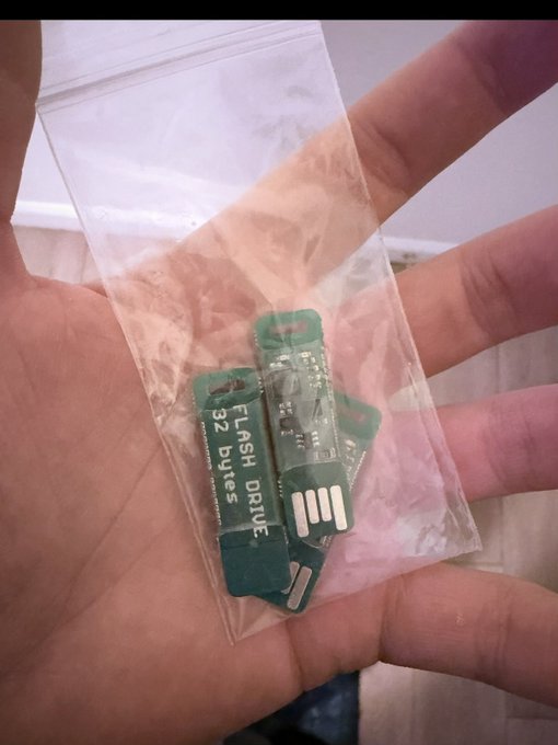A hand holds a small clear plastic bag containing several green USB-shaped Opendime hardware wallets, with one labeled "FLASH DRIVE 32 bytes." The image relates to the post's mention of using Opendimes, the small USB Bitcoin wallets from Coinkite known for their sealed design and one-time-use spending mechanism.