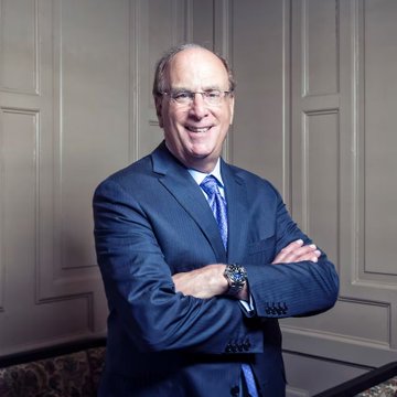 A man in a blue suit and tie stands smiling with arms crossed in front of paneled walls, representing the institutional financial perspective discussed in the post. The accompanying quote from Larry Fink, CEO of BlackRock, highlights how major institutions are now embracing Bitcoin after years of skepticism, signaling a significant shift in the asset's legitimacy.