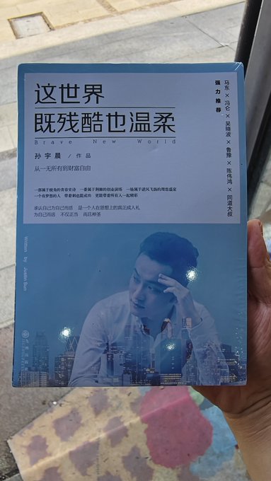 A person displays the novel "这世界既残酷也温柔" (Brave New World) by 孙宇晨 (Sun Yuchen), related to the post's mention of hoping to get a signature from "孙哥" (Brother Sun) and tagging @sunyuchentron. The book's cover features a contemplative portrait of a young man against a city skyline.