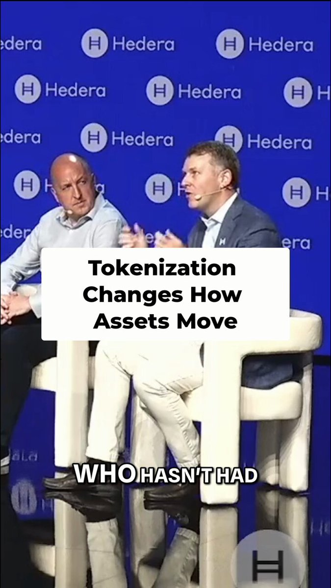 The image shows two men sitting next to each other at a table, talking about tokenization changes. The text "Tokenization Changes How Assets Move" is displayed above them, indicating their conversation topic.