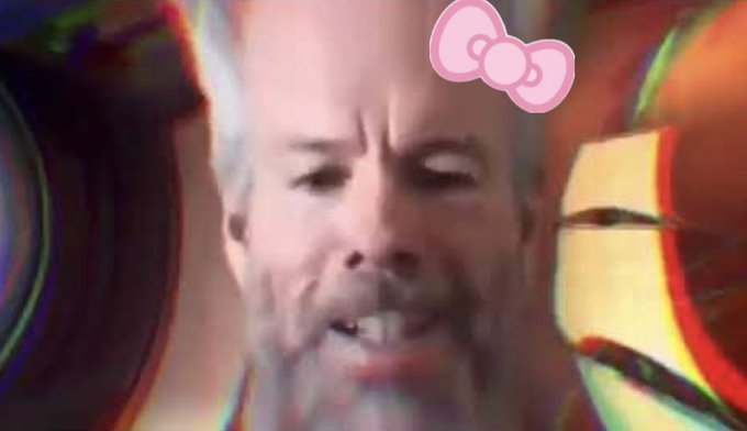 A glitchy, psychedelic edit of a man's face with a pink bow sticker, visually emphasizing the "kawaii" or "cute" aesthetic associated with cat-themed meme coins. The colorful distortion and added bow reinforce the playful, meme-driven community spirit referenced in the caption about cat coin supporters confidently predicting massive market caps.