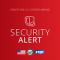 A red "SECURITY ALERT" banner from "UPDATE FOR U.S. CITIZENS ABROAD" featuring a shield-and-key icon, with "STOP" text below an American flag. The image ties into the post's message about using Travel Mode to protect personal data, suggesting that failing to secure your device can expose U.S. citizens abroad to security risks.