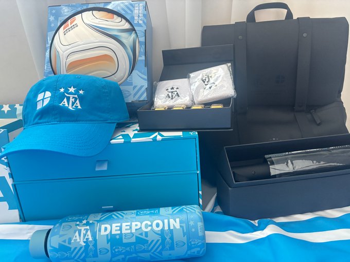 A promotional merchandise bundle featuring a blue AIA soccer ball, an 'AIA' branded cap, a navy backpack, a water bottle labeled 'AIA DEEPCOIN', and a gift box with items inside.