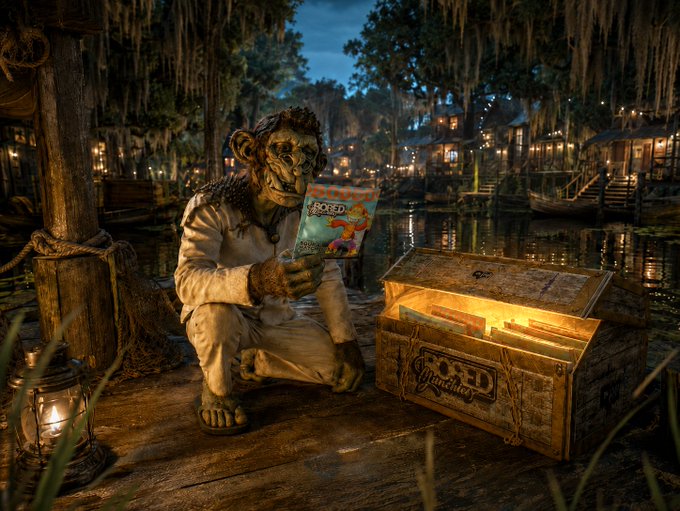 A moss-covered, pirate-like creature wearing a tattered shirt crouches on a swampy dock at night, examining a bag of "Bored Munchies" snacks pulled from a treasure chest bearing the same "Bored Munchies" branding. The scene playfully illustrates the post's theme of "treasures never meant to stay buried," with the glowing snacks replacing traditional gold as the loot of a Bayou-set adventure.