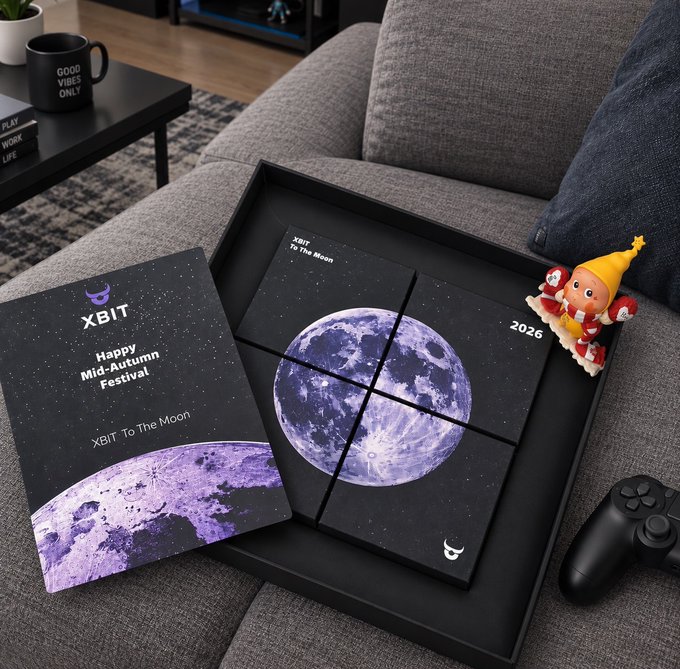 An XBIT cryptocurrency gift box set titled 'Happy Mid-Autumn Festival 2026' with 'XBIT To The Moon' featuring a moon design on a couch next to a PlayStation controller.