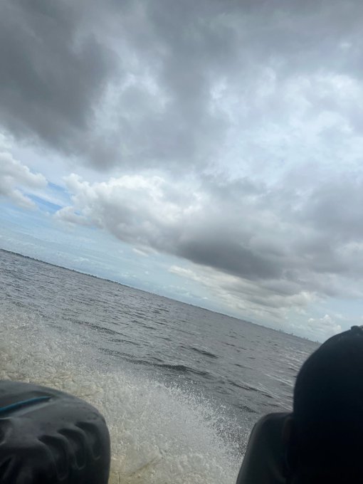 A view from a boat showing ocean waves and a cloudy sky, with dark figures in the foreground.