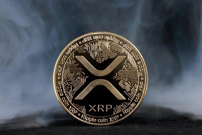 A gold XRP/Ripple coin is displayed against a smoky, atmospheric background, visually representing the cryptocurrency poised for a historic Nasdaq listing. The image ties directly to the post's announcement of 473 million XRP heading toward a Nasdaq debut under the ticker XRPN on October 8.