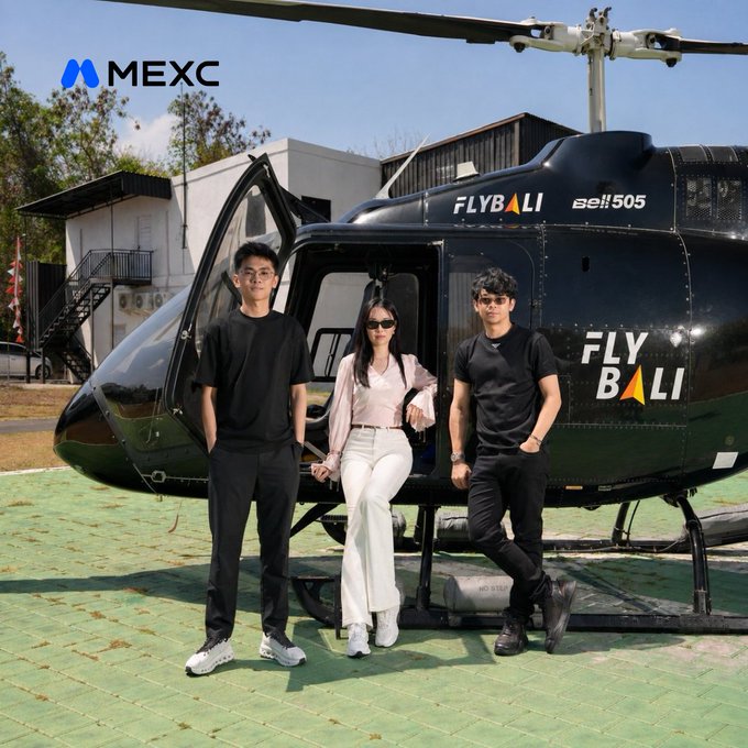 Three stylishly dressed individuals pose in front of a sleek black helicopter branded with "FLY BALI" and "Bell 505," with the MEXC logo displayed in the top left corner—visually capturing the exclusive, VIP "POV" moment referenced in the post's hashtag #MEXCEventRocks.