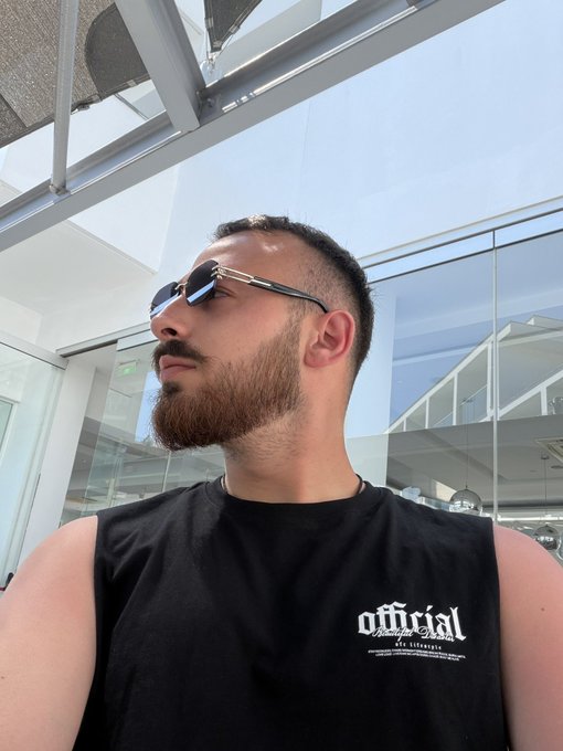 A man with a beard and sunglasses poses confidently in front of a modern glass building, wearing a black tank top that reads "official." The image pairs with the post's bold crypto prediction, projecting a confident, forward-looking vibe to match the claim of an imminent historic bull run.