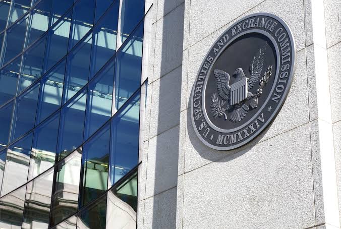 The image shows the U.S. Securities and Exchange Commission (SEC) seal mounted on the exterior of a modern glass and stone building. The seal features an eagle, the words "U.S. SECURITIES AND EXCHANGE COMMISSION," and the Roman numerals "MCMXXXIV" (1934, the year the SEC was established). The image relates to the post by visually representing the regulatory body at the center of the dispute over Nasdaq's proposed QBTC Bitcoin options, highlighting the SEC's role in pausing the approval amid CME Group's legal challenge.