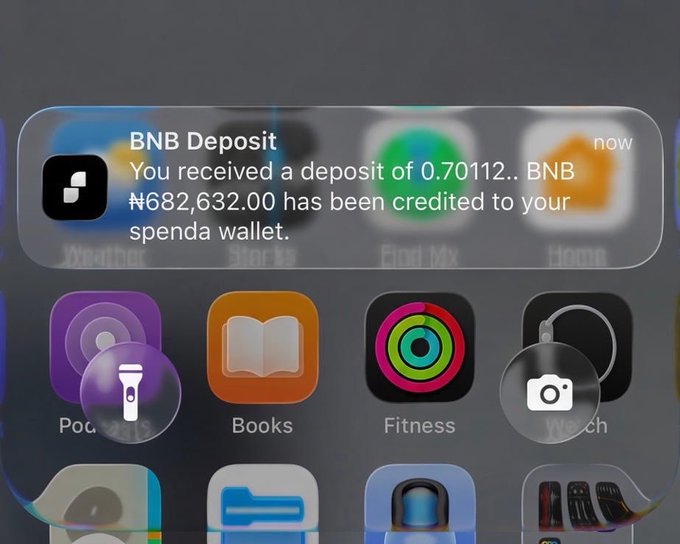 An iPhone lock screen notification showing a BNB deposit of ₦682,632.00 credited to a Spenda wallet, with various app icons visible below.