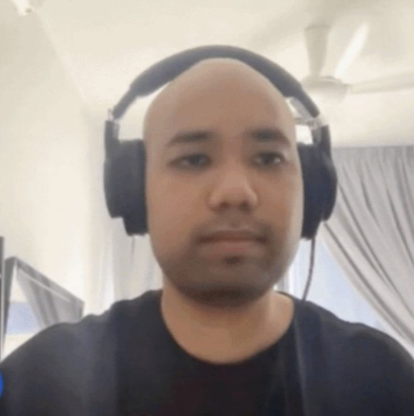 The image shows a bald man wearing headphones, possibly playing video games or listening to music. He appears to be focused on something outside of the frame, with his head tilted slightly to the side. The caption reads "can i sleep on your couch if bitcoin goes to zero? thankiu very muchie". This suggests that the man is engaged in an activity related to Bitcoin and its value, possibly discussing or analyzing it while wearing headphones for a more immersive experience.