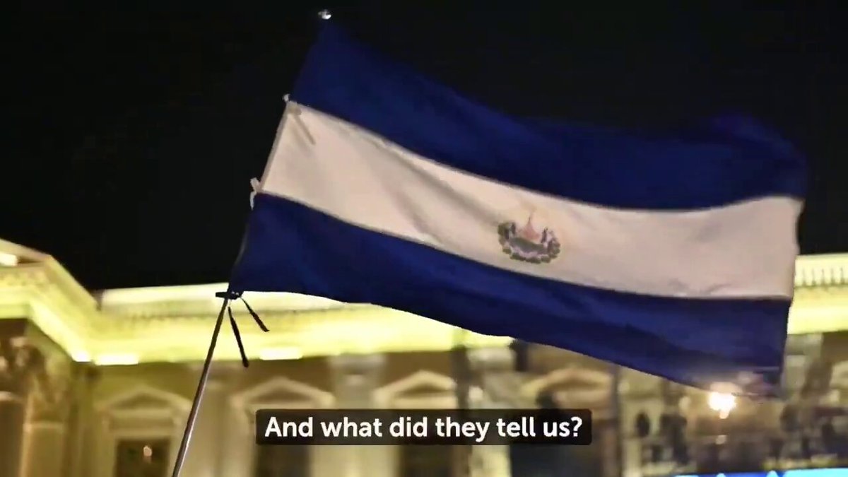 The image features a flag with blue, white, and green colors flying high above a building at night. The caption below the image reads "And what did they tell us? 90 days residence is required global game theory at work". This suggests that there might be some sort of discussion or event related to the flag's symbolism in relation to international relations or global politics.