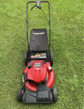 A red Troy-Bilt self-propelled lawn mower sits on a grassy lawn, appearing to be in nearly new condition with its black collection bag and engine housing intact. The mower was found discarded and picked up for free, as referenced in the post's "#TrashToCashToSATs" series about reselling curbside finds.