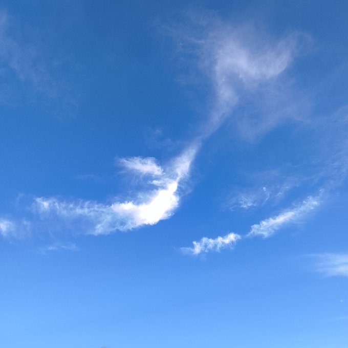 A view of a clear blue sky featuring a uniquely shaped white cloud formation.