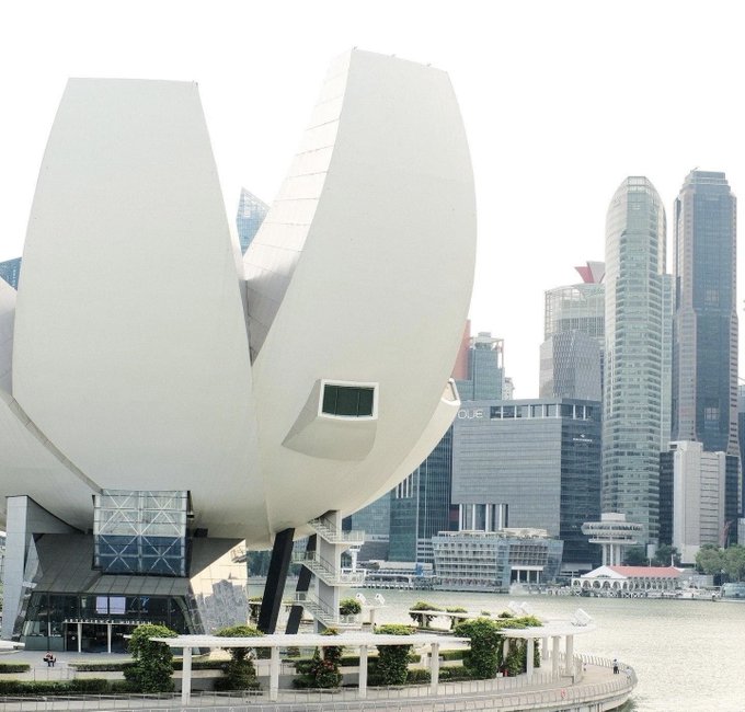 The image shows the ArtScience Museum in Singapore with its distinctive lotus-shaped white architecture against a backdrop of the city's CBD skyline. This relates to the post because it depicts Singapore, where police have issued warnings about job recruitment scams targeting cryptocurrency and tech workers with fraudulent high-paying job offers.