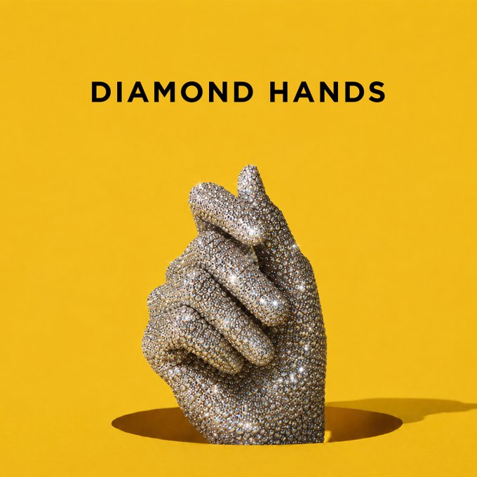 The image features the text "DIAMOND HANDS" above a pair of hands clasped together, encrusted entirely in glittering diamonds, set against a vibrant yellow background. It visually represents the crypto slang "diamond hands," which refers to holding onto investments despite volatility—fitting the post's playful reference to needing strong hands to hold crypto assets.