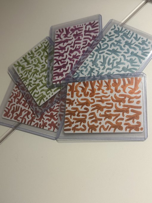 Five tile coasters with abstract squiggly patterns are displayed fanned out in plastic cases. The designs feature different color schemes including green, purple, blue, red, and orange.
