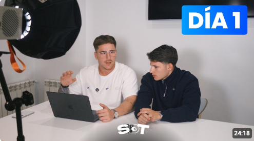 Two men in casual clothing sit at a white desk with a laptop, filmed under studio lighting, with a "DÍA 1" graphic and a timer showing "24:18" displayed on screen. The image captures the early episode ("Day 1") of their podcast, reflecting the post's message about how starting the podcast two years ago opened their minds to new trading perspectives.