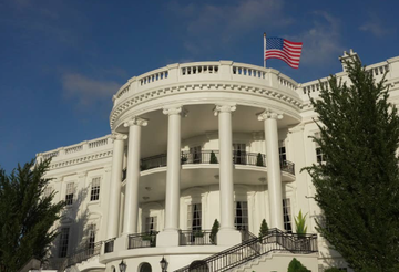 The image shows the White House's South Portico, identifiable by its distinctive curved colonnade and American flag flying against a blue sky. The post appears to relate to a high-level meeting at the White House involving SEC Chairman Paul Atkins, CFTC Chairman Michael Selig, and crypto industry leaders, with the building symbolizing the federal government's central role in the discussions.