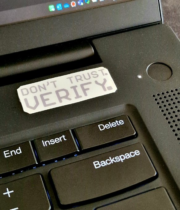 A laptop keyboard features a sticker reading 'DON'T TRUST. VERIFY.' placed above the End, Insert, Delete, and Backspace keys.