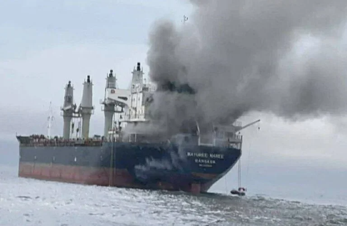 A large cargo ship named "MATTHEW MAREE BANGKOK" engulfed in smoke and fire on the water.