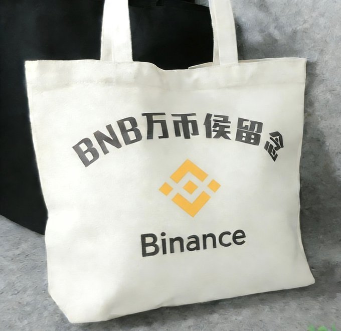 A cream-colored tote bag displaying 'BNB万币候留' in gray Chinese characters alongside the yellow Binance logo and 'Binance' text, placed against a gray background.