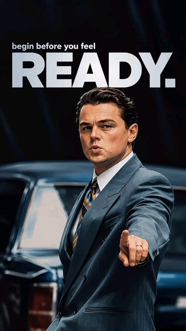 A motivational poster featuring a man in a gray suit pointing at the viewer, with text reading 'begin before you feel READY.' above him.