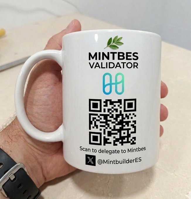 A hand holds a white mug branded with the "MINTBES VALIDATOR" logo, a QR code, and the text "Scan to delegate to Mintbes" along with the X handle "@MintbuilderES." The mug promotes the Mintbes Validator for staking $ONE on the Harmony network, as referenced in the post highlighting an 11.12% expected return.