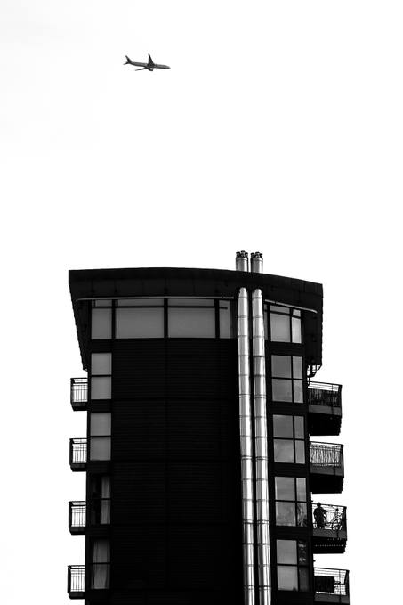 A black-and-white photo shows a modern high-rise building with balconies and a small airplane flying overhead. The image appears to accompany a “Good morning Home Sweet Home 6” post promoting the $XTZ token on objkt.com.