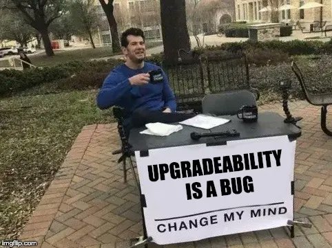A meme image showing a man sitting at a 'CHANGE MY MIND' table outdoors with a sign reading 'UPGRADEABILITY IS A BUG'.