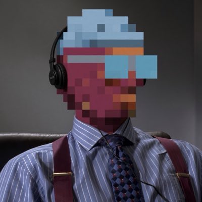 A man wearing a striped shirt, tie, and suspenders has his face obscured by a pixelated/mosaic block wearing headphones and pixelated sunglasses.