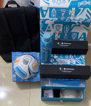 FIFA World Cup merchandise is displayed, including a black Adidas backpack, an official match soccer ball, a blue tumbler, and branded boxes with the trophy logo.