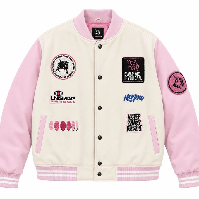 A pink and cream varsity-style bomber jacket with pink sleeves, displayed flat, featuring various patches including ones reading "SWAP ME IF YOU CAN", "NSWAP", "MORPHO", and "SWEET SWAP RED CAT".