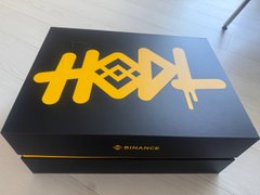 A black Binance-branded box with a gold graphic design on top, sitting on a light surface.