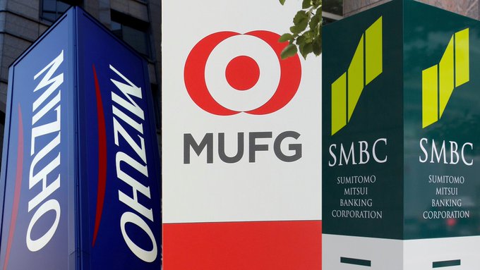 The image shows three different bank logos displayed side-by-side against a brown background. The logos are for MUFG, SMBC, and Mizuho banks. The text at the bottom of the image reads "BREAKING: Japan'S three largest banks, MUFG, SMBC and Mizuho, plan to jointly issue a stablecoin by March 2027." This indicates that there is an upcoming event related to these banks in Japan, possibly involving the release of a new stablecoin.