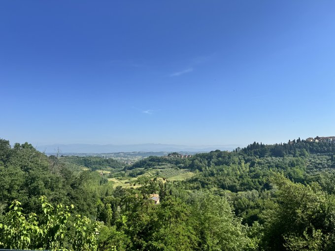 The image shows a beautiful view of a valley with trees, hills, and mountains in the background. The sky above appears blue, suggesting that it's a clear day. The scene evokes feelings of tranquility and appreciation for nature. The caption provided seems unrelated to the image itself but might be there as part of an automated response or as part of a promotional effort.
