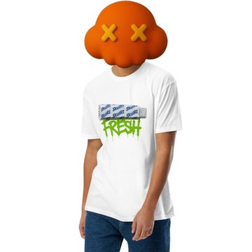 A person models a white t-shirt with green graffiti-style text reading 'REAL', a graphic design above it, while wearing a distinctive orange cloud mask with X's for eyes.