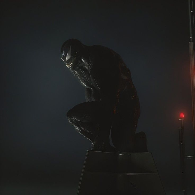 A crouched, glossy black Venom figure perches on a pedestal in dramatic low lighting, with its menacing white eyes and toothy grin illuminated against the dark background and a small red warning light glowing to the right.