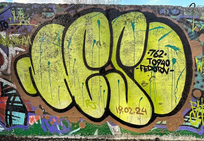The image shows a vibrant graffiti piece with the large yellow bubble-letter tag "NESO," accompanied by the text "762," "T0940," "-FEDOTOV," and the date "19.02.24." This relates to the accompanying post as it showcases a piece of graffiti potentially eligible for the NESO graffiti NFT collection check on OpenSea.